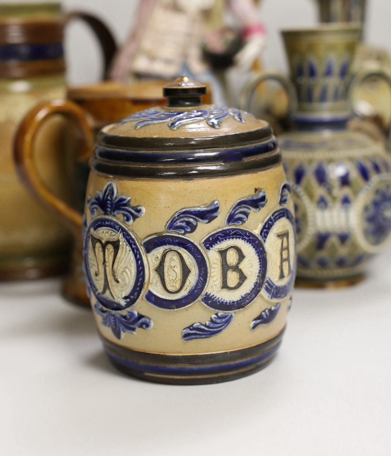 A group of six Doulton Lambeth stoneware vessels, tallest 22.5 cm and a French porcelain figure of a gentleman (7)